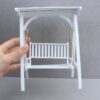 Miniaturowa huśtawka trzymana w dłoni dla pokazania skali