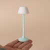 Miniaturowa lampa podłogowa z miętową nóżką na dłoni dla skali