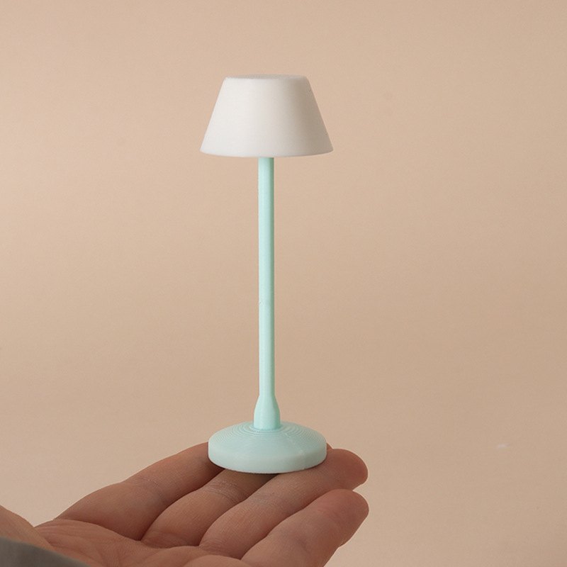 Miniaturowa lampa podłogowa z miętową nóżką na dłoni dla skali