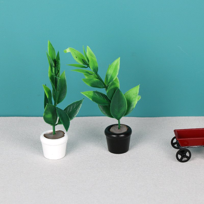 Rośliny w doniczkach obok miniaturowego wózka ogrodowego