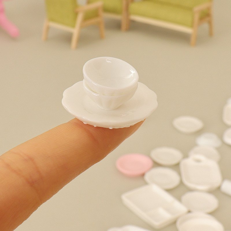 Miniaturowa biała miseczka na talerzyku ustawiona na czubku palca