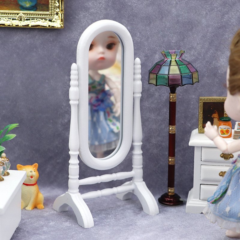 Miniaturowe lustro z lalką w odbiciu obok lampy i szafki
