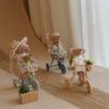 Pluszowe myszki na miniaturowych rowerkach trójkołowych w stylizowanej scenie