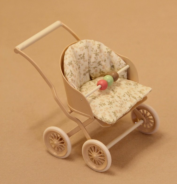 Miniaturowy wózek spacerowy z drążkiem z koralikami na brązowym tle